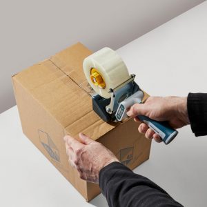 hands using a tape dispenser on a cardboard box