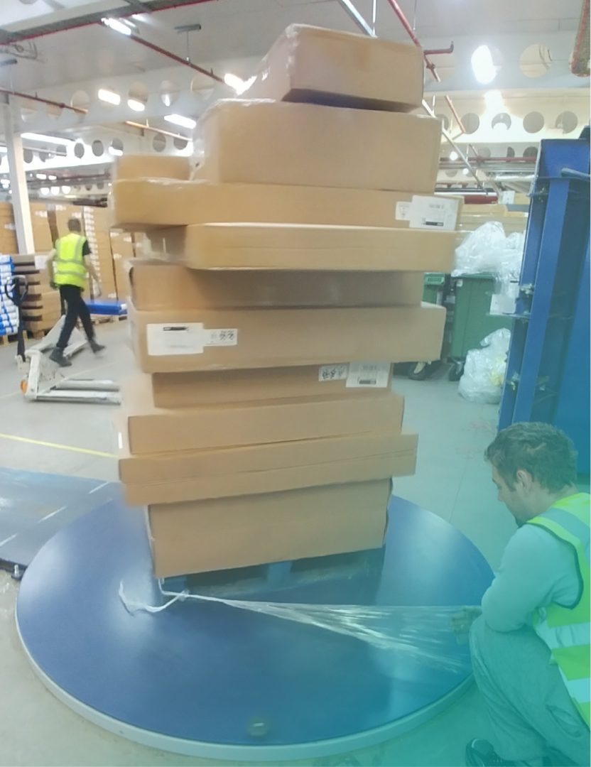 cardboard boxes piled on top of each other being plastic wrapped