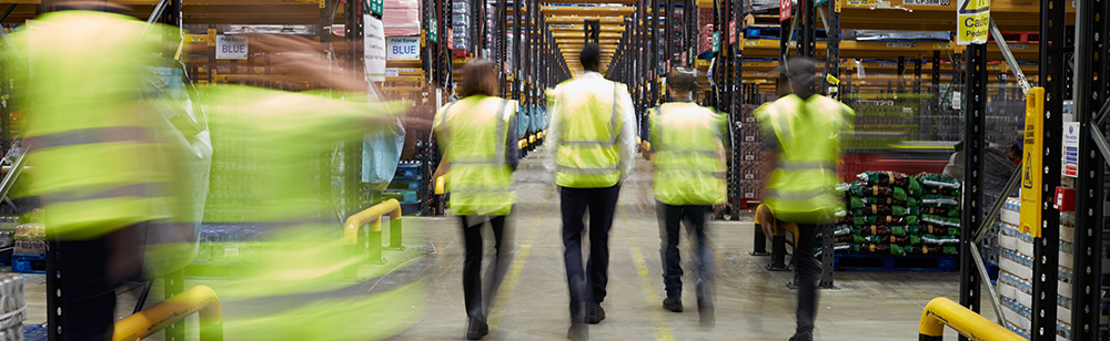 Staff in reflective vests walking in a warehouse
