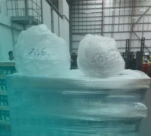 pallet wrapped in plastic wrap with two balls of wrap with writing - 746g on the larger and 475g on the smaller